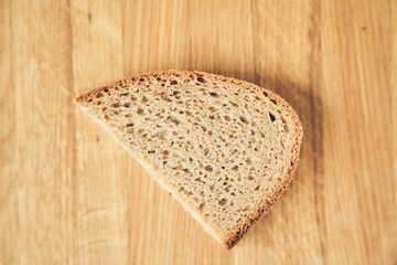 One slice of dark gluten-free rye bread on a wooden board background with space to copy. High quality photo