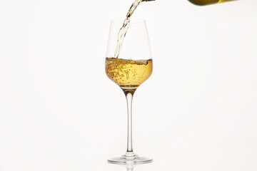 White wine pouring from green bottle on white isolated, close up.