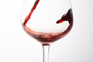 Red wine stream flows, swirls in glassware bowl.