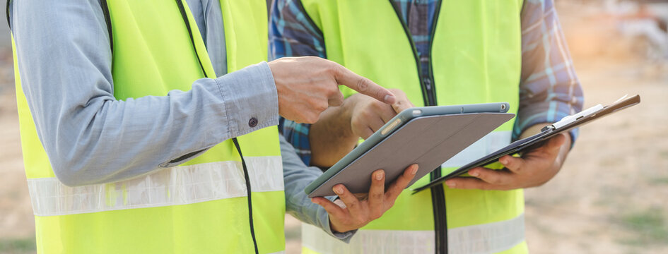 Builder engineer and supervisor consultant inspection job plan  concept, Asian contractor and foreman looking blueprint in computer laptop and checking process plan of factory warehouse construction