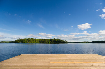 A spacious wooden dock gracefully stretches into the serene waters of a tranquil lake in Muskoka,...