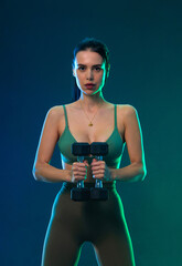 Sporty fit woman, athlete with dumbbells make fitness exercises on neon background. Download cover for music collection for fitness classes. Sports recreation. Beautiful black young woman.