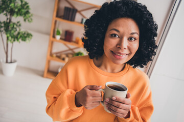 Photo portrait of lovely young lady drink coffee beverage dressed casual orange clothes cozy day light home interior living room - obrazy, fototapety, plakaty