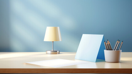 An empty sheet of paper on a wooden desk next to a lamp and a cup of pencils in front of a blue background wall with sunlight shining from the left.