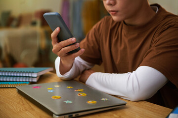 Cropped image of teenager watching short videos on smartphone instead of studying