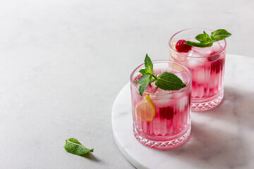Raspberry cocktail with ice in a glass on a light background