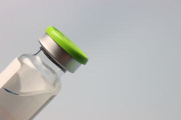 Drug vial in the left side been hold by a person wearing glove with a copy space in the right. Close up view of a dug vial