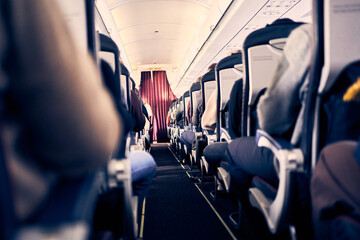 The cabin of a commercial aircraft with rows of seats along the aisle. Morning light in the cabin...