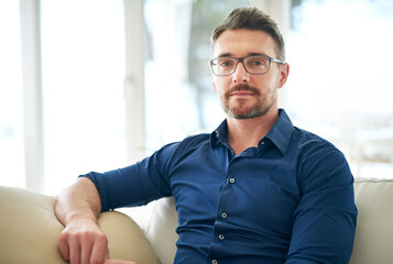 Obraz premium Businessman, glasses and portrait on sofa in airport for work, relax and out of town startup project. Male person, corporate and unwind on couch in waiting room for international, travel and company