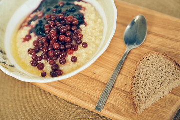 Millet for breakfast. There is a warm wheat porridge with red currants and blueberry jam on the table. A plate of wheat porridge for a healthy gluten-free breakfast. High quality photo