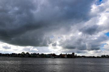 Canal in the Zaanse Schans Netherlands area, the town in the background. Sky full of black clouds.