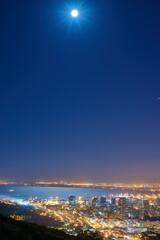 Cityscape, building and coastal lights and night view or location as urban infrastructure, development or sea. Skyscrapers, sky and moon or evening with downtown journey or Miami travel, trip or town