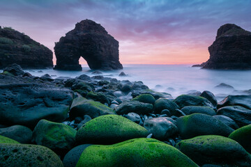 Beautiful landscape with a rocky arch and ocean beach at sunset