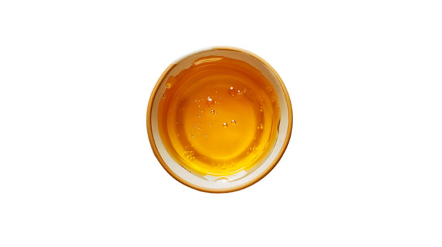 
A top-down view of honey in an empty glass bowl, isolated on a white background