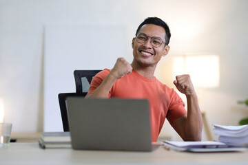 A man who is happy and excited when he succeeds in hard work in his home office, working at home.