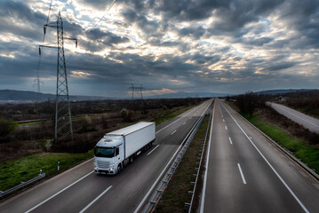 White transportation truck on a countryside highway under a dramatic sunset sky