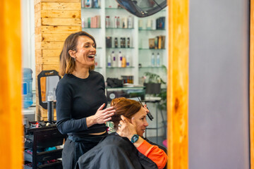 Hairdresser laughing while talking with a customer