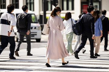 ビジネス街の横断歩道を渡る日本人女性の後ろ姿