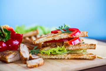 fried toast with chicken, salad, greens on a wooden table