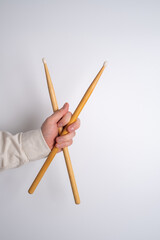 Man is holding wooden drumsticks on a light background. Music and hobby concept