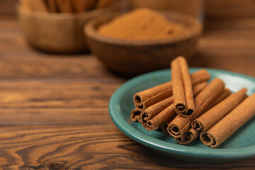 Cinnamon sticks on a textured wooden background. Cinnamon roll. Spicy spice for baking, desserts and drinks. Fragrant ground cinnamon. cinnamon powder Close-up. Place for text. copy space