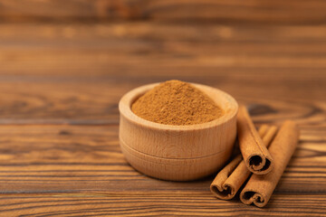 Cinnamon sticks on a textured wooden background. Cinnamon roll. Spicy spice for baking, desserts and drinks. Fragrant ground cinnamon. cinnamon powder Close-up. Place for text. copy space