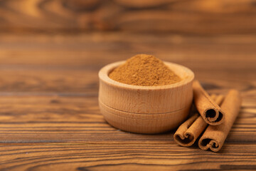 Cinnamon sticks on a textured wooden background. Cinnamon roll. Spicy spice for baking, desserts and drinks. Fragrant ground cinnamon. cinnamon powder Close-up. Place for text. copy space