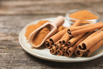 Cinnamon sticks on a textured wooden background. Cinnamon roll. Spicy spice for baking, desserts and drinks. Fragrant ground cinnamon. cinnamon powder Close-up. Place for text. copy space