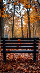 A park bench sits in a park with fallen leaves all around it. The trees are bare, and the leaves are a variety of colors, including orange, yellow, and red. The bench is empty, and there is a path lea - obrazy, fototapety, plakaty