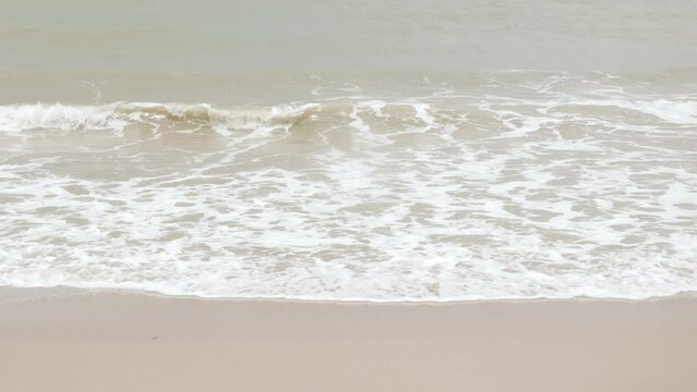 close up to Sea waves rolling over the fine sand beach, waves break on white sand beach with beautiful foam, tropical summer vacation holiday nature background