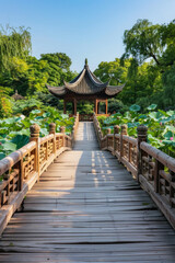 Fototapeta premium A wooden bridge in a lotus pond, with a Chinese pavilion in the background 