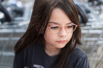 Portrait of a cute little girl with glasses on the street.