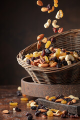 Mix of various nuts and raisins in a old basket on a brown background.