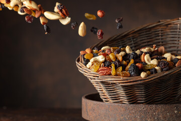 Mix of various nuts and raisins in a old basket on a brown background.