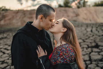 beautiful and young lovers, a guy and a girl are walking on an unusual terrain similar to the moon. Happy couple of European appearance on a first date in nature, smiling and relaxing
