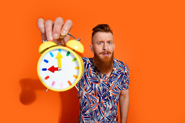 Photo of shocked impressed guy dressed print shirt showing you clock isolated orange color...