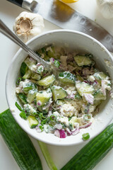 Feta cheese salad with cucumber, red onions and chives. Marinated with olive oil on white table ...