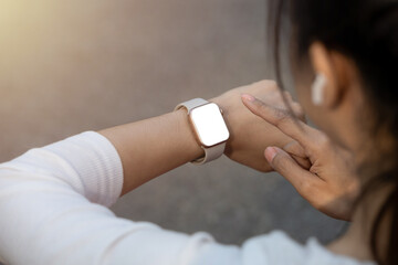 Close-up of a runner's wrist wearing a smartwatch, monitoring her performance with wireless earbuds.