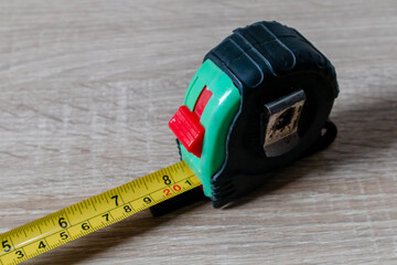 Roll up metal tape measure on a wooden background