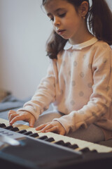 A little girl plays the electric piano.