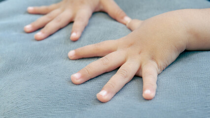 Little child hands with ten fingers on the gray sofa