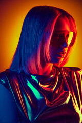 High-fashion. Portrait of beautiful young girl in sunglasses and metallic dress against gradient orange yellow background in neon light. Concept of modern fashion, contemporary trends, beauty, youth