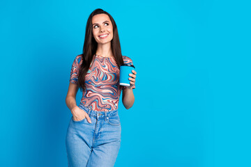 Photo portrait of pretty young girl hold paper cup coffee look empty space wear trendy colorful clothes isolated on blue color background - obrazy, fototapety, plakaty
