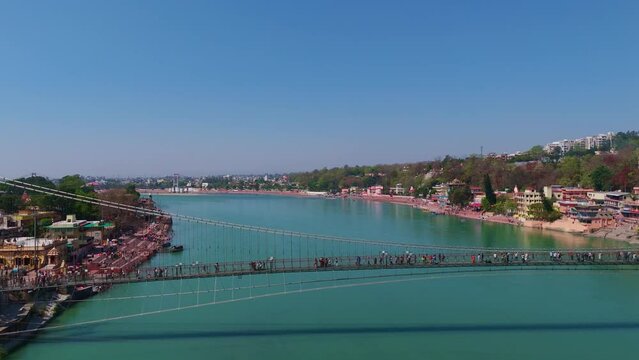 people crossing bridge in rishikesh drone shot