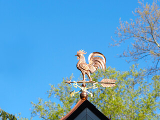 Copper rooster weathervane against blue sky