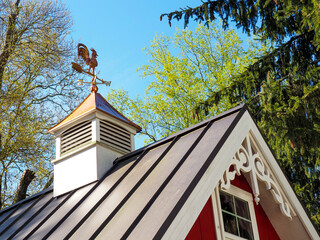 Copper rooster weathervane and cupola on red shed or barn with dark metal roof © Jaybird Blue