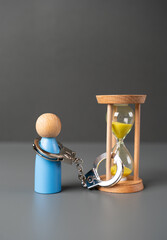 A man is handcuffed to an hourglass. Limited time. Conditions of a contract. Imprisonment and imprisonment for a period. Time remaining in life. - obrazy, fototapety, plakaty