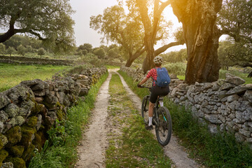 active senior woman cycling with her electric mountain bike in the rough landscape of National Parc Serra de São Mamede near Marvao in central Portugal, Europe - 795369580