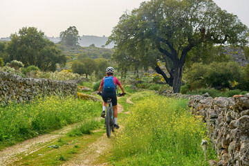 active senior woman cycling with her electric mountain bike in the rough landscape of National Parc Serra de São Mamede near Marvao in central Portugal, Europe - 795369938