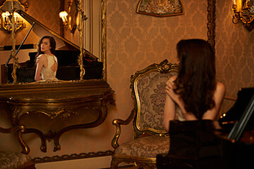 Woman, piano and reflection with mirror in antique home for classy fashion, style or music. Young,...